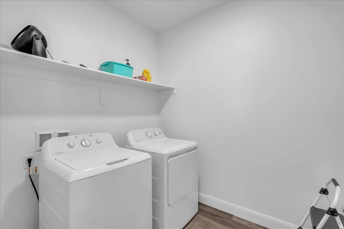 Dedicated laundry area featuring a shelf, wood-finish flooring, and white baseboards