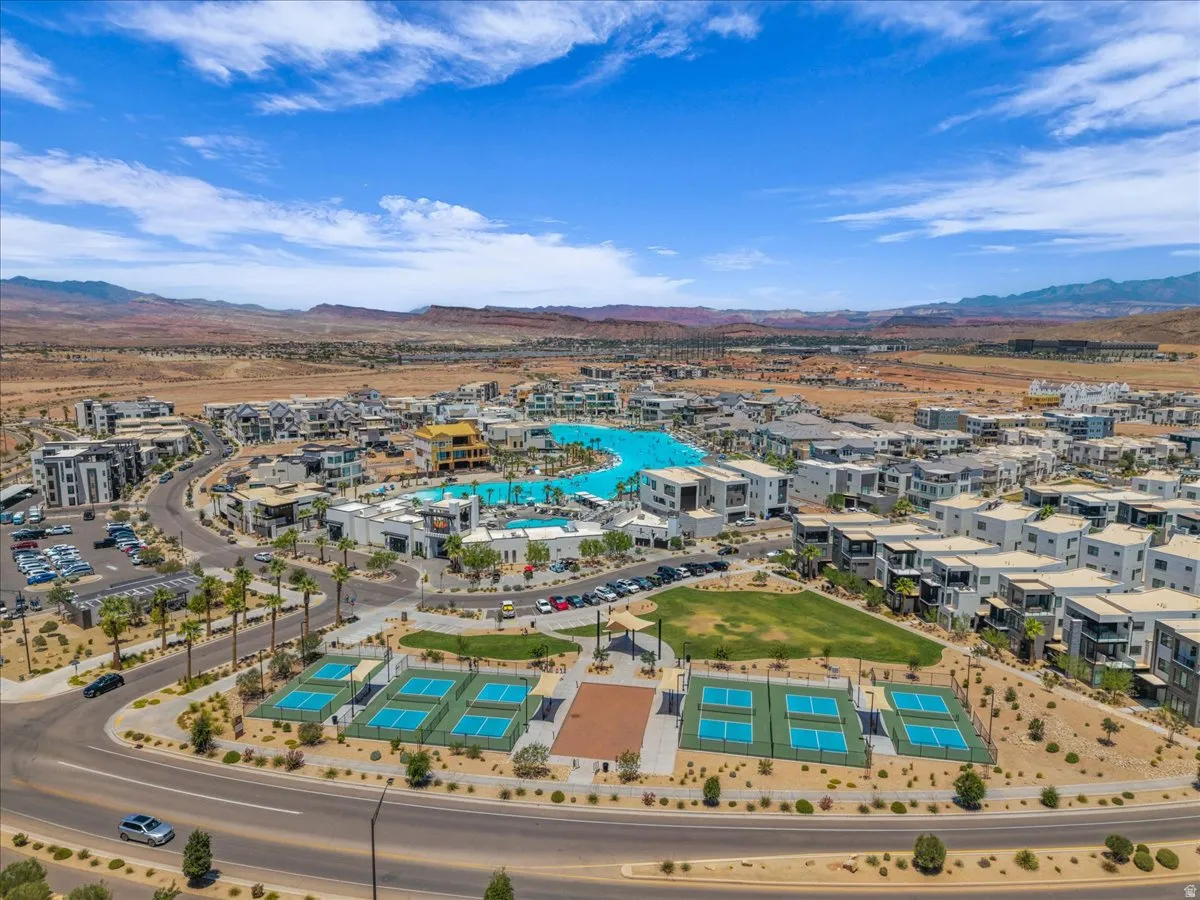 Aerial perspective showcasing a modern community with a large lagoon-style pool, multiple pickleball courts, and expansive green spaces