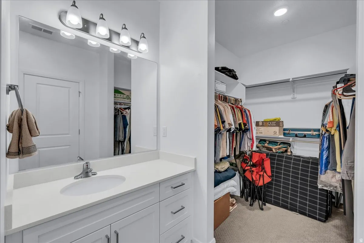 Bathroom vanity featuring a single undermount sink, a white countertop, and white cabinetry with brushed nickel hardware
