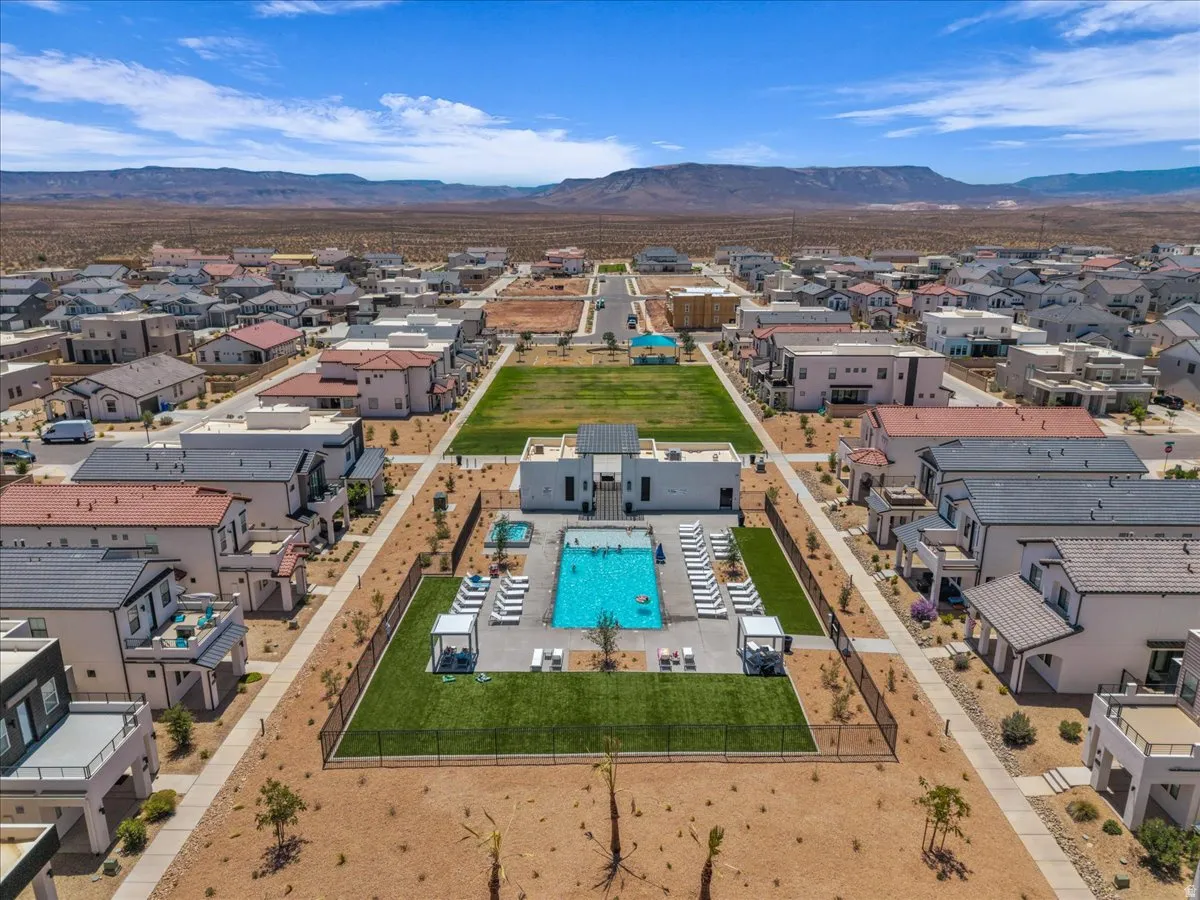 Community amenity featuring a central swimming pool, surrounding lounge areas, and a manicured turf lawn
