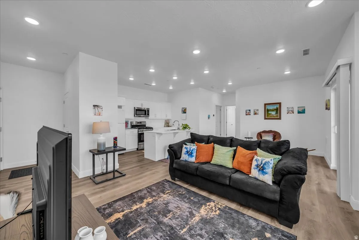 Open-concept living space featuring wood-finish flooring, recessed lighting, and white walls