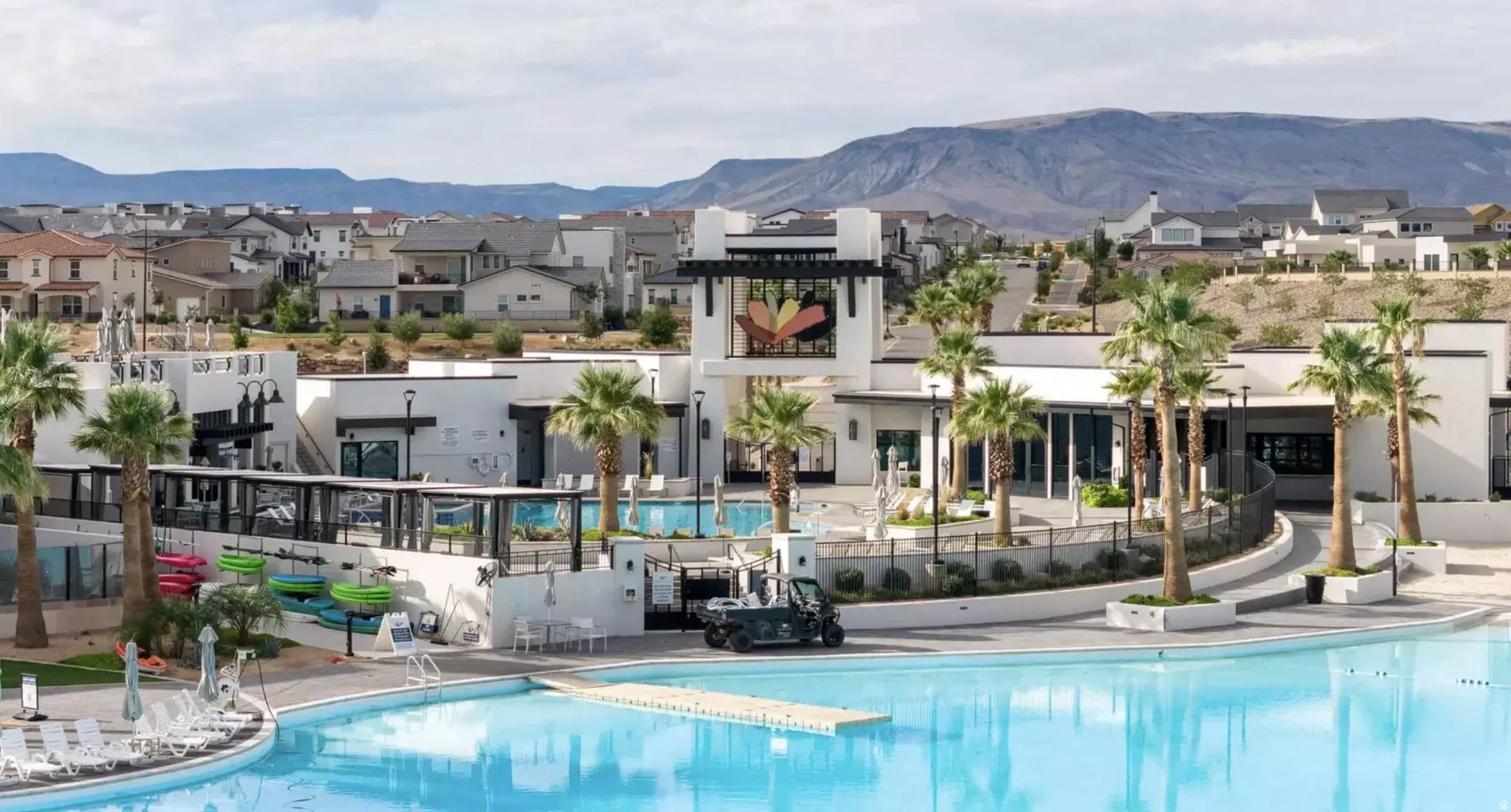 Expansive resort-style swimming pool featuring a large deck with lounge seating and a multi-level clubhouse with modern architectural elements