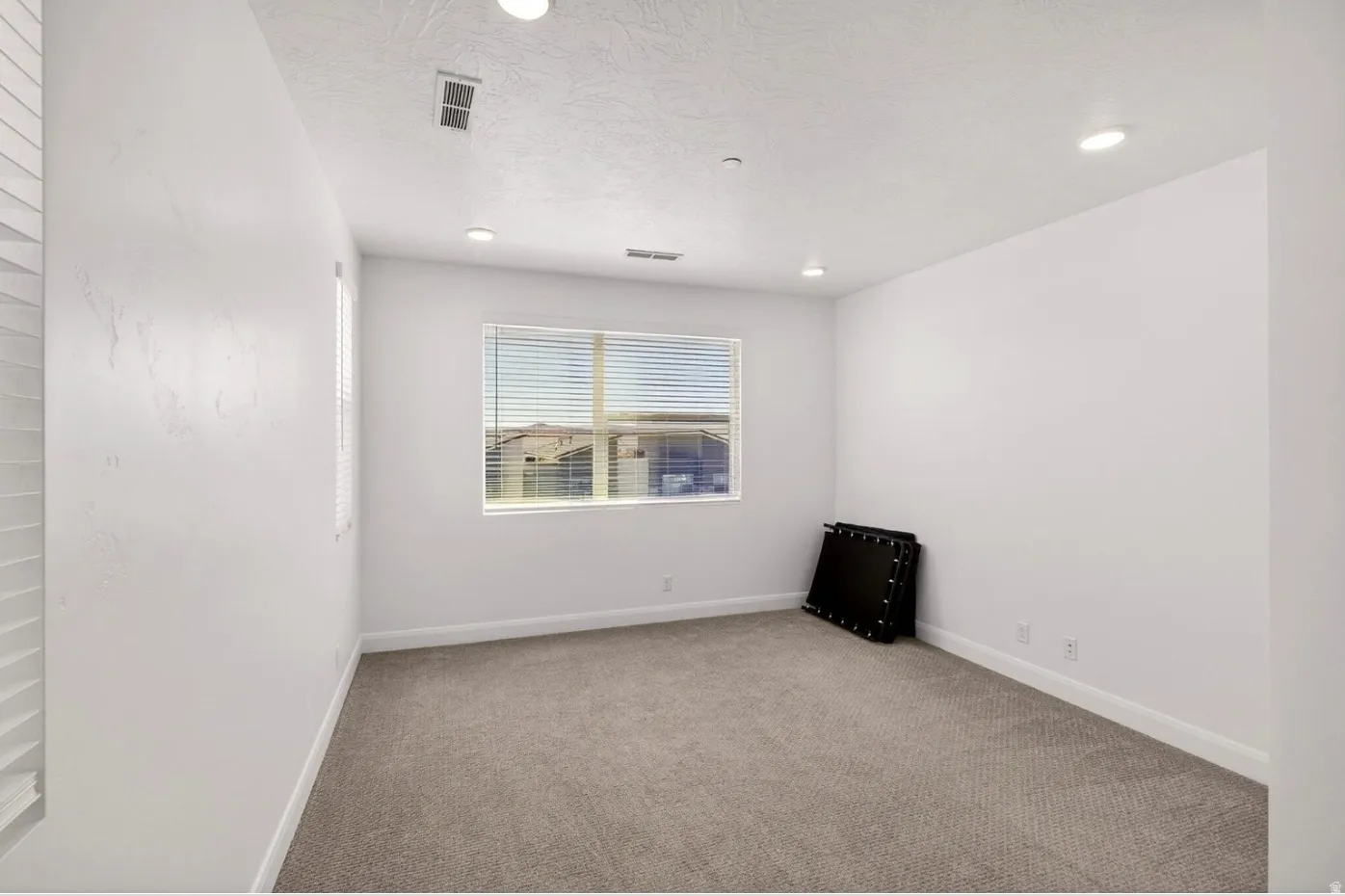 Carpeted room featuring a large window with horizontal blinds, recessed lighting, and white baseboards