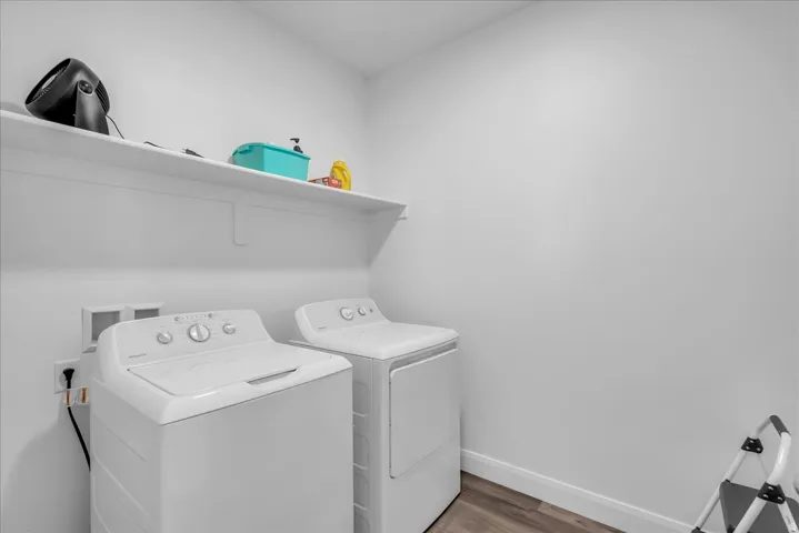 Dedicated laundry area featuring a shelf, wood-finish flooring, and white baseboards
