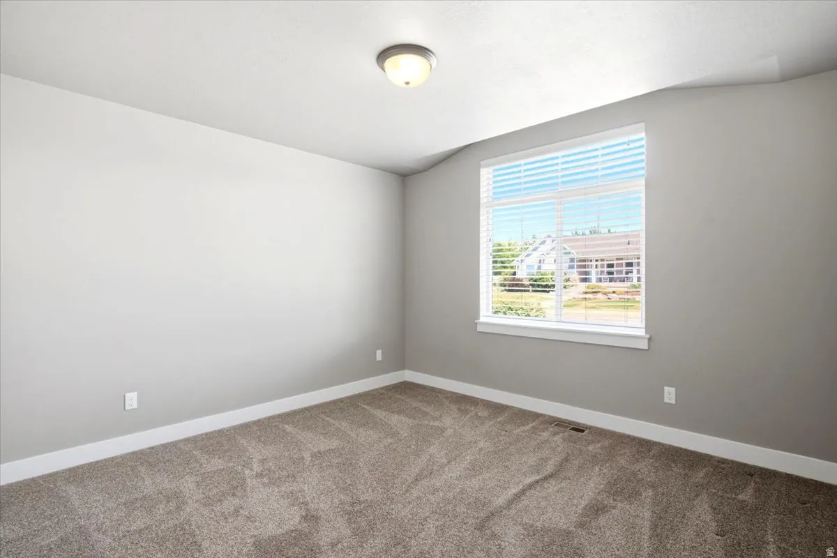 Carpeted room featuring a large window with white blinds, neutral gray walls, and white trim