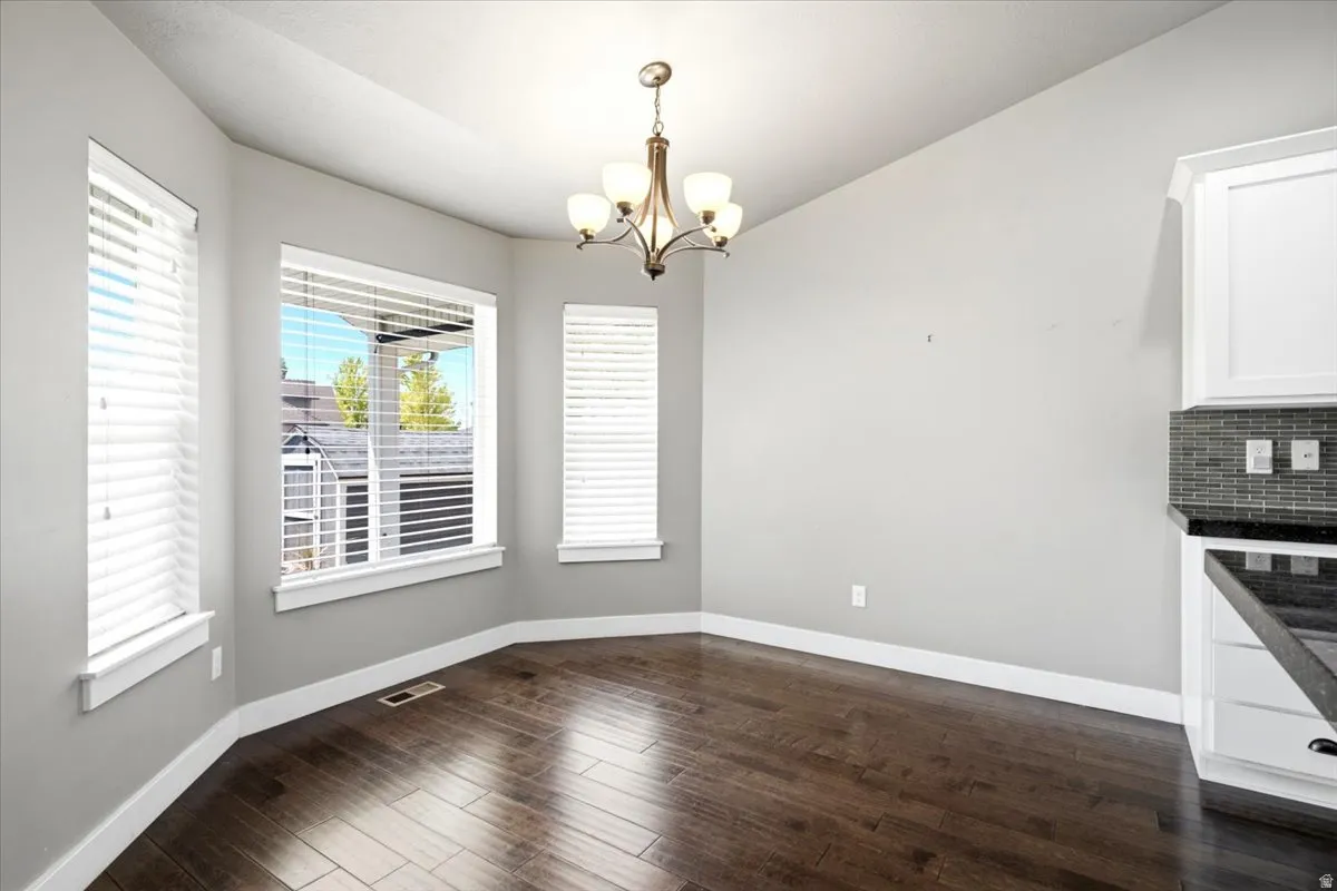 Dining area featuring wood-finish flooring, a tiered chandelier, and a bay window configuration