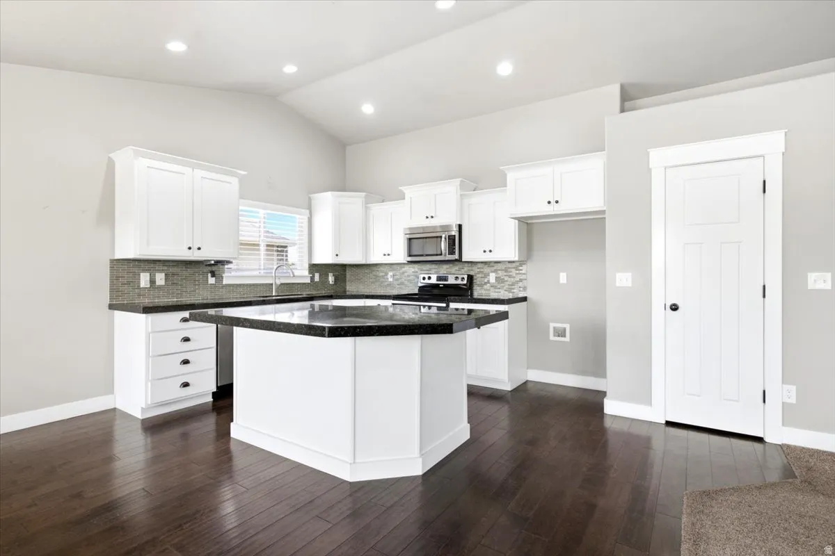 Kitchen featuring white cabinetry, dark countertops, and a tile backsplash