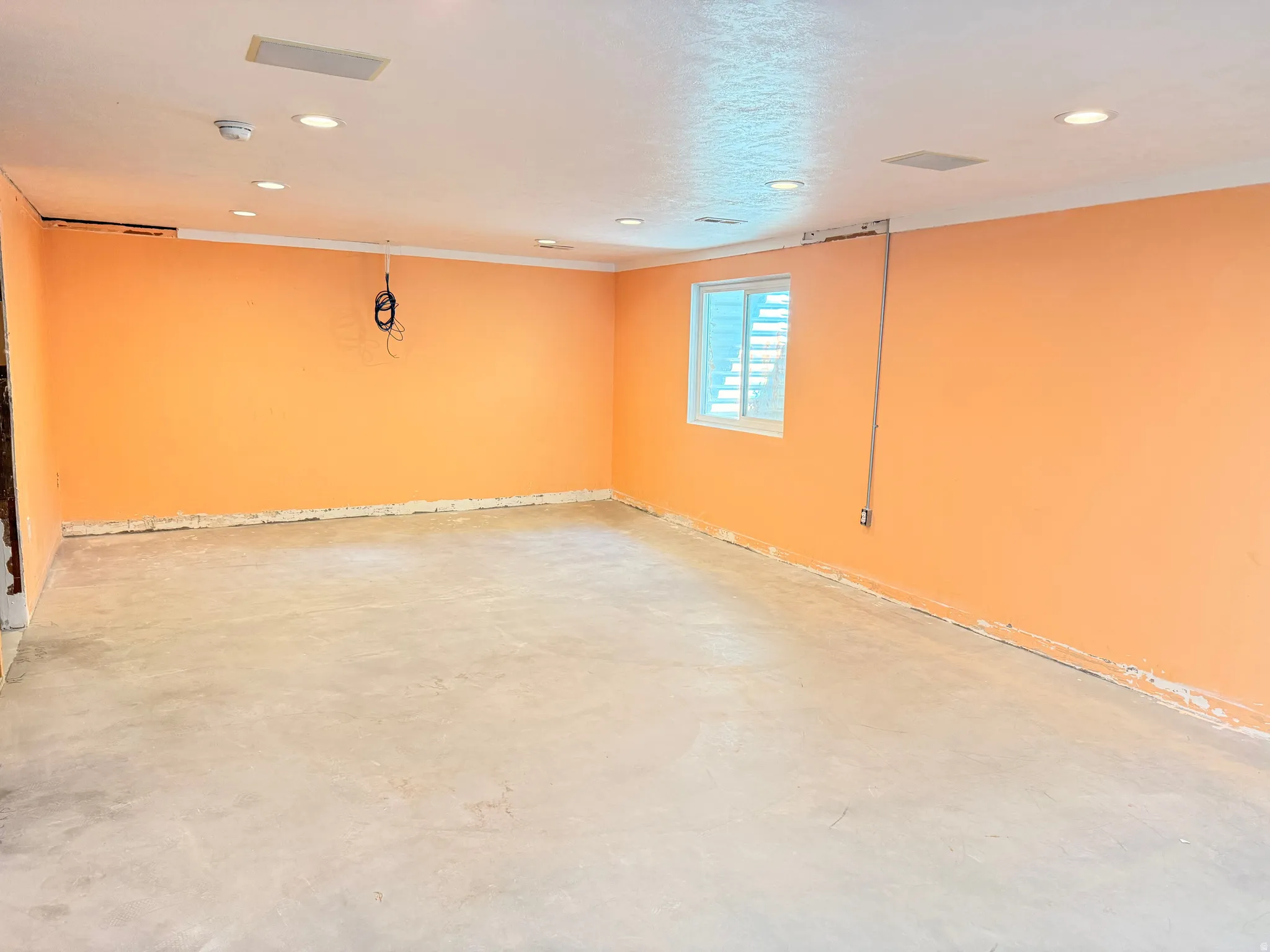 Recessed ceiling lighting, ceiling-mounted speakers, and a window with horizontal blinds