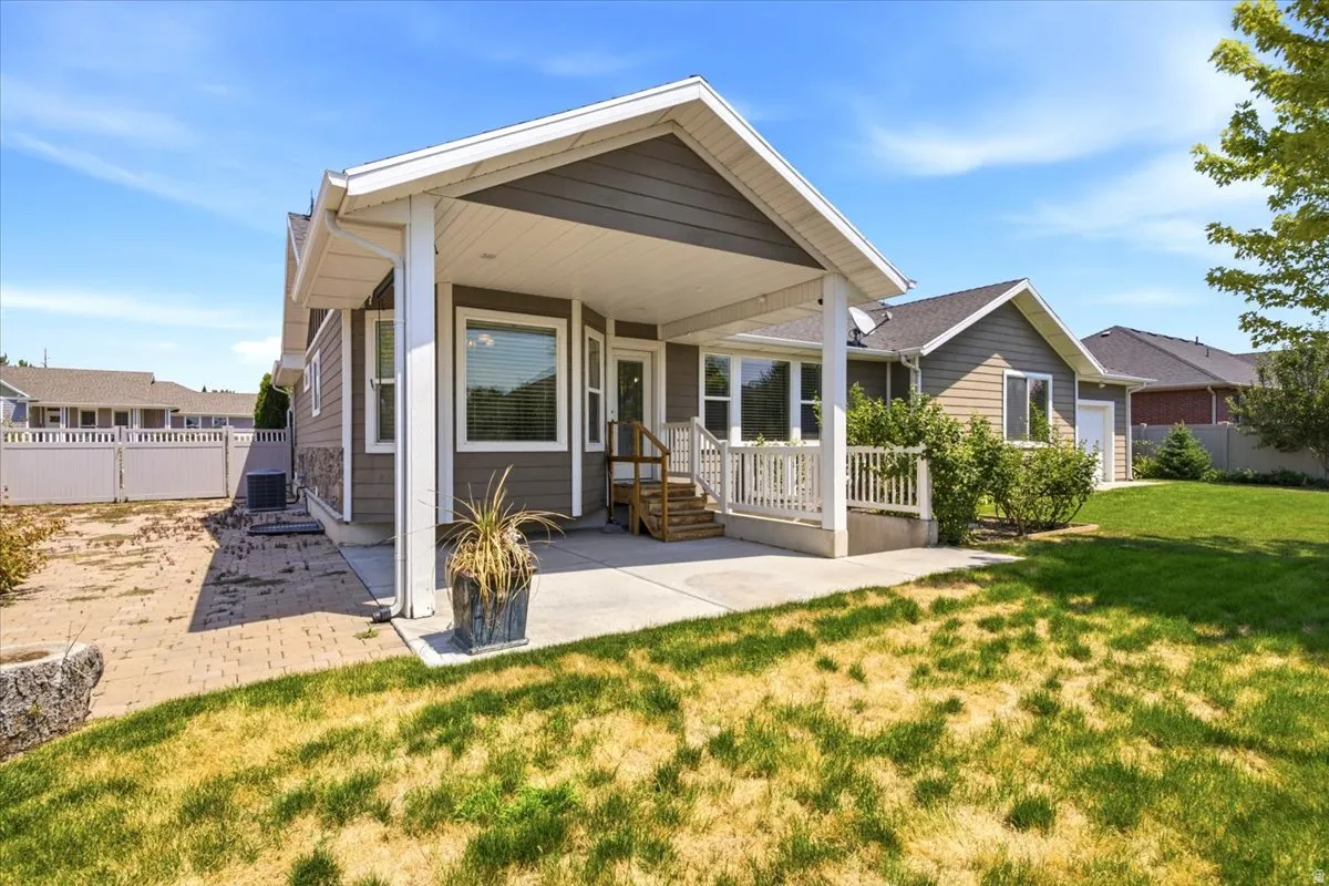 Covered patio area with concrete flooring, accented by a white railing and supporting columns