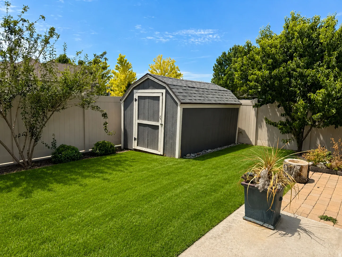 Spacious rear yard featuring an accessory storage shed with an asphalt shingle roof