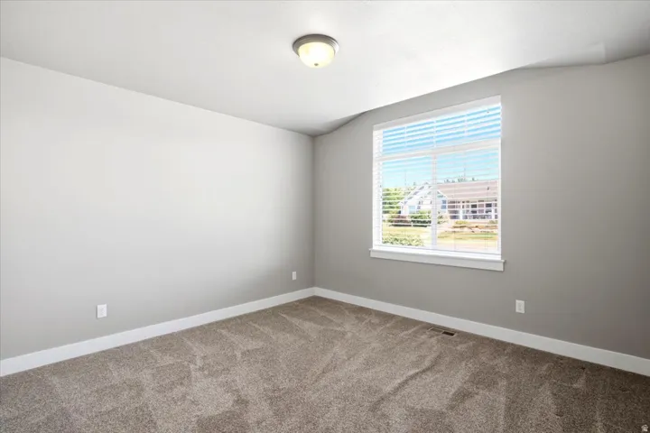 Carpeted room featuring a large window with white blinds, neutral gray walls, and white trim