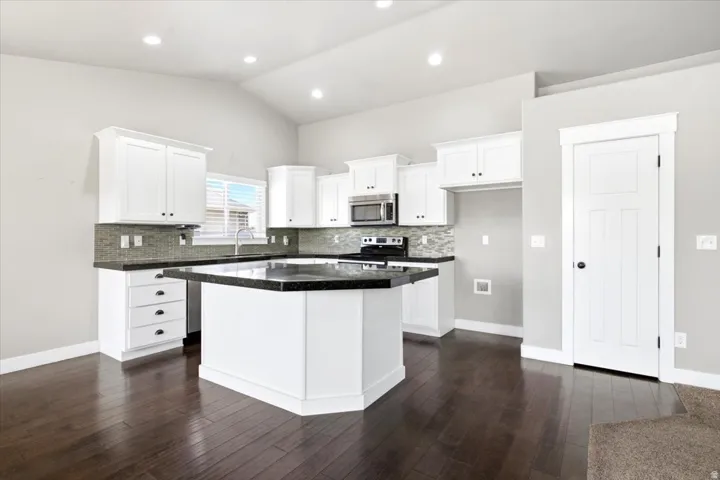 Kitchen featuring white cabinetry, dark countertops, and a tile backsplash