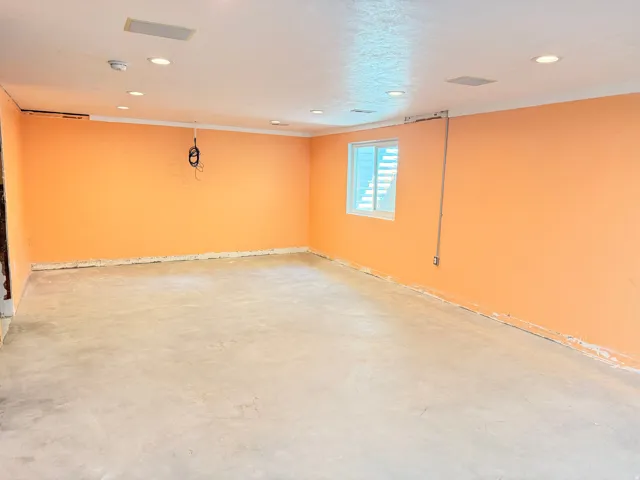 Recessed ceiling lighting, ceiling-mounted speakers, and a window with horizontal blinds