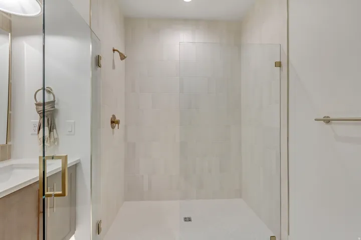 Walk-in shower with clear glass enclosure and brass hardware