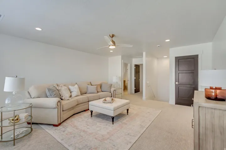 Recessed lighting illuminates the carpeted living area with a ceiling fan