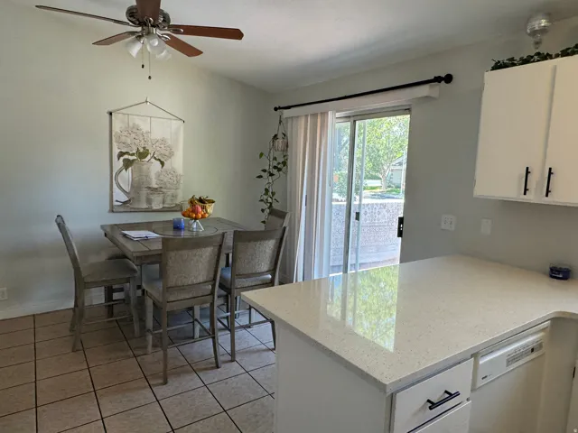 Kitchen area featuring a white countertop with integrated dishwasher, white cabinetry with matte black hardware, and tiled flooring
