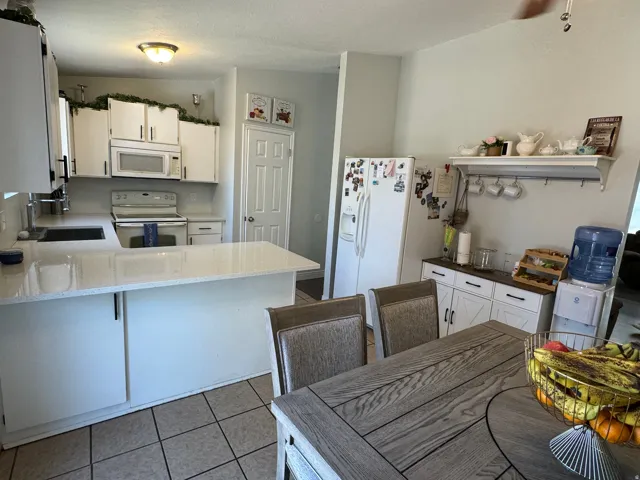 Kitchen featuring white cabinetry, light-toned countertops, a built-in microwave, and tile flooring