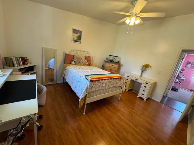 Interior room featuring wood-finish flooring, a ceiling fan with integrated lighting, and neutral wall tones