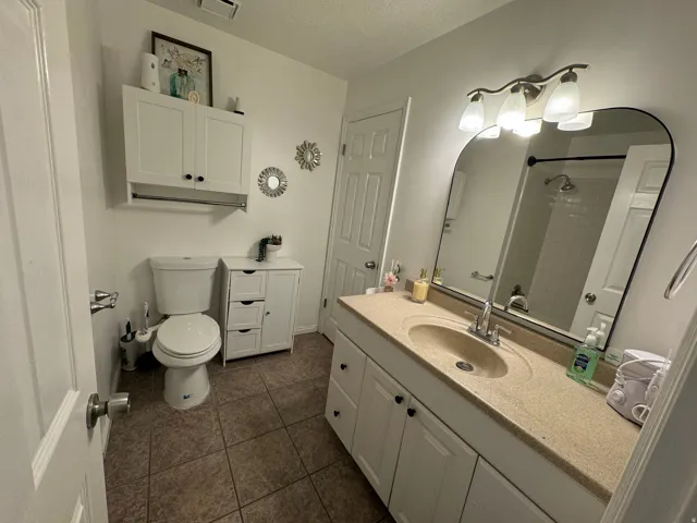 Bathroom featuring a single vanity with an integrated sink, a large wall-mounted mirror, and a three-light fixture