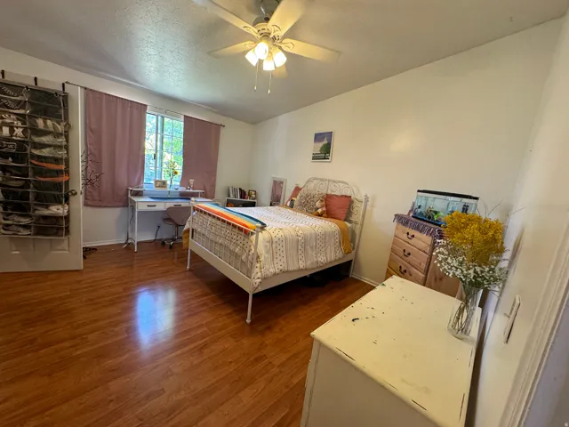 Bright interior space featuring wood-finish flooring, a window with natural light, a ceiling fan with integrated lighting, and white baseboards