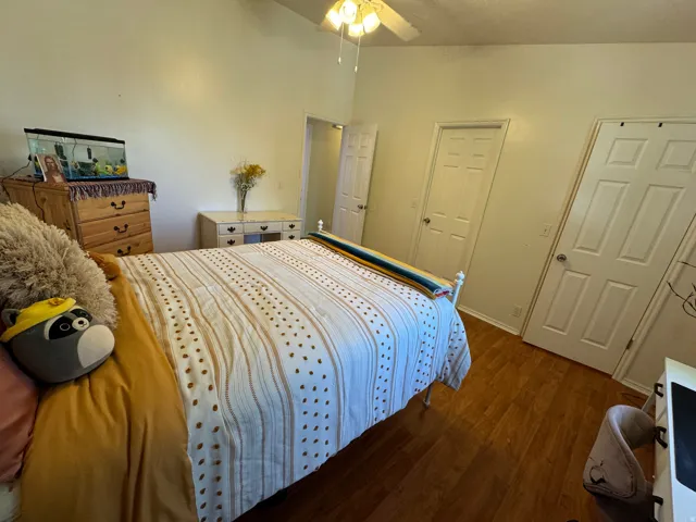 Bedroom featuring wood-finish flooring, a vaulted ceiling, and a ceiling fan with integrated lighting