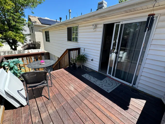 Exterior deck with wooden railings and a sliding glass door entry to the building