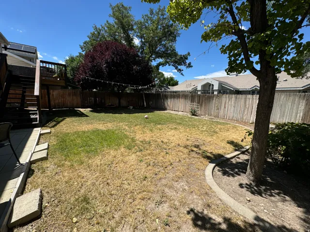 Expansive backyard featuring a multi-level wood deck, wood privacy fencing, and mature trees