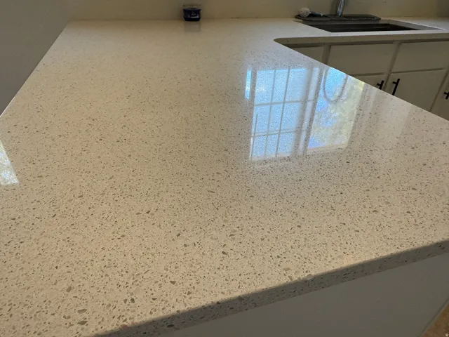 Expansive kitchen countertop featuring a speckled white composite surface and an integrated sink with a chrome faucet