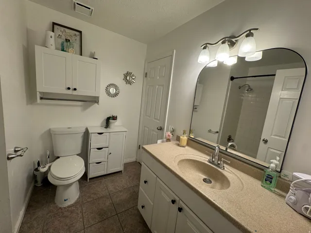 Bathroom vanity featuring an integrated sink with a single-handle faucet, a large wall-mounted mirror, and a four-light fixture