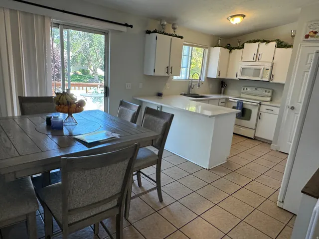 Kitchen featuring white cabinetry, light-toned countertops, and a full suite of white appliances
