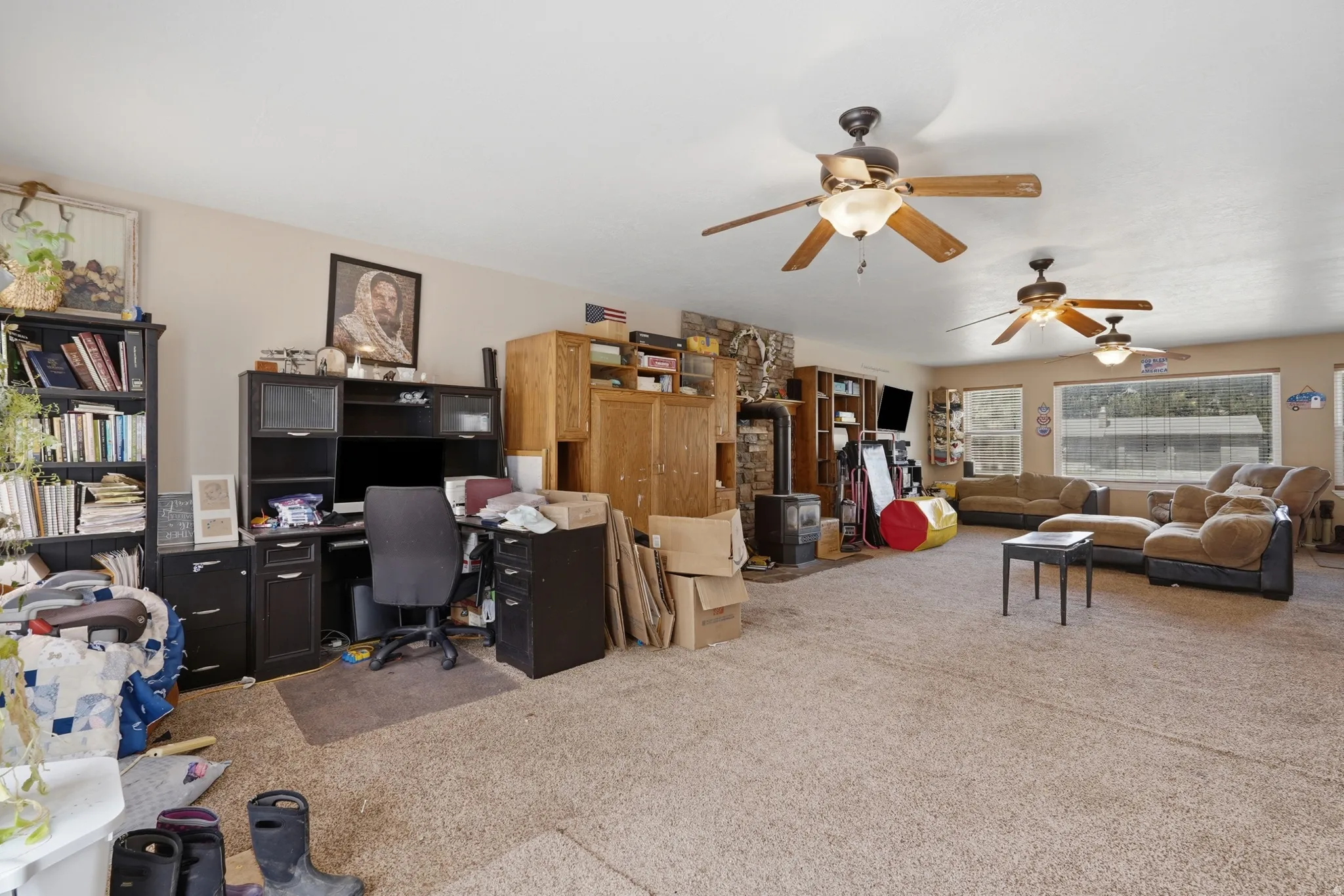 Spacious room featuring neutral carpeting and multiple ceiling fans for comfort
