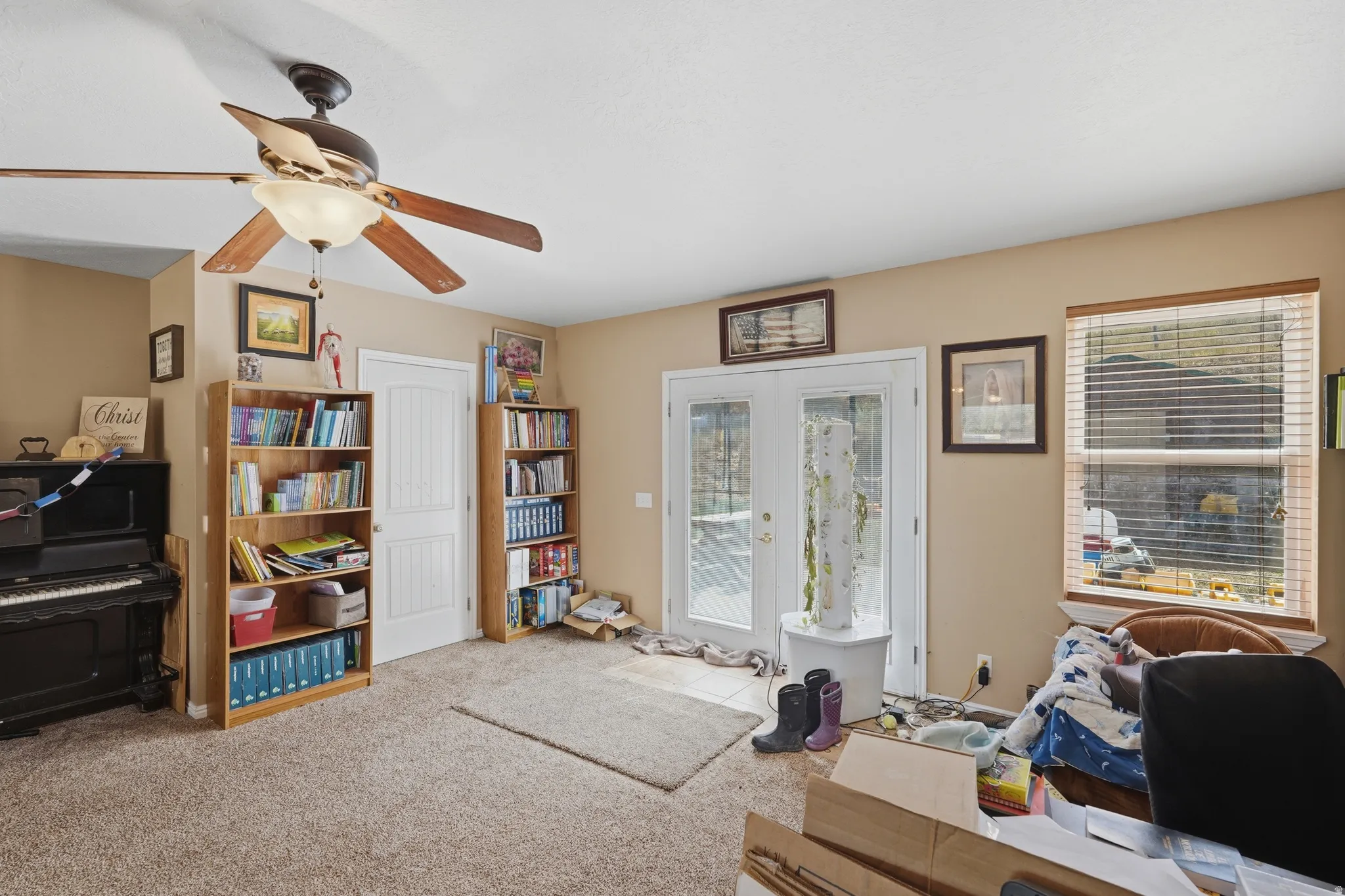 Carpeted room featuring a ceiling fan with light fixture, double pane windows, and light-toned walls