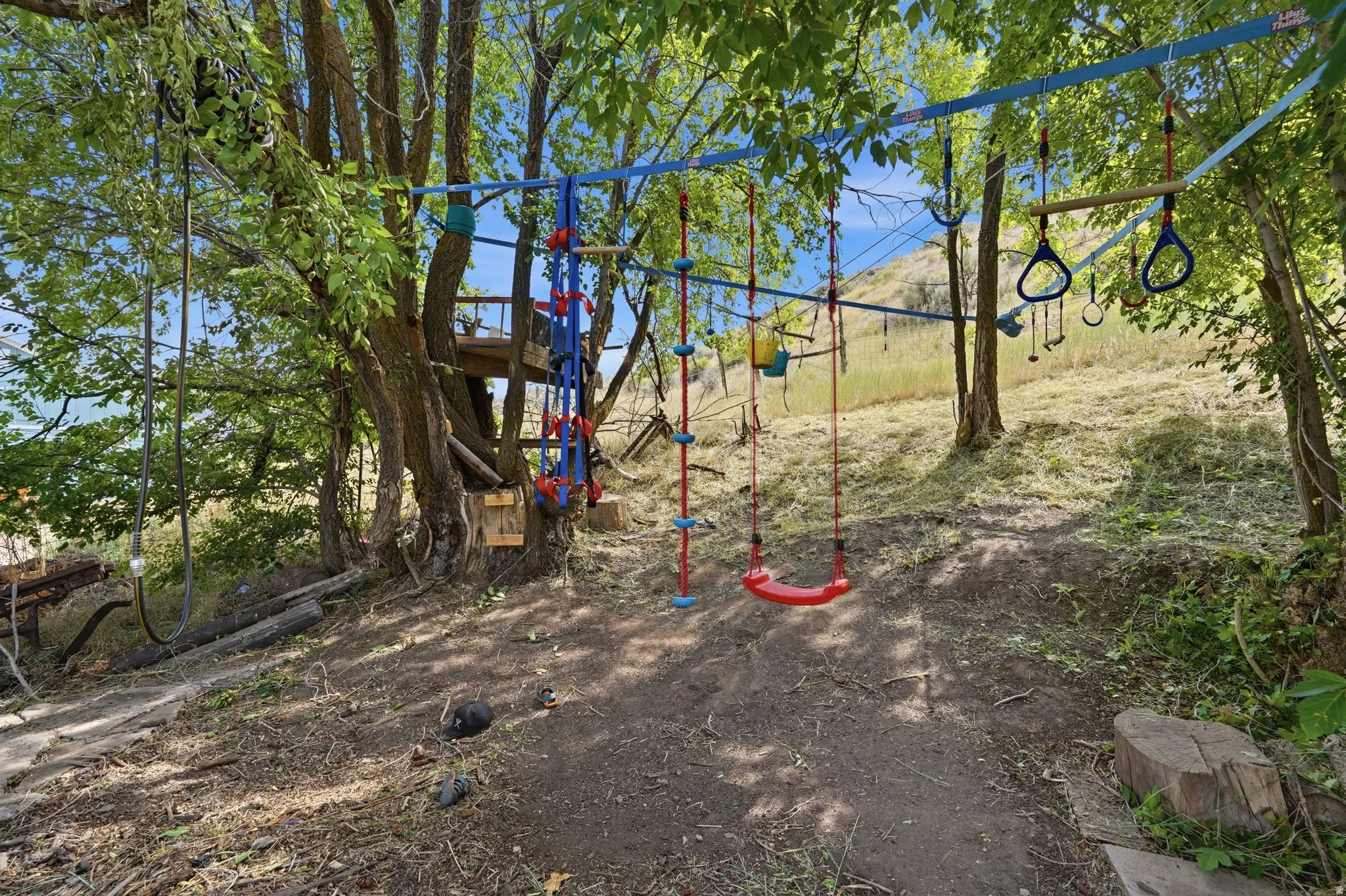 Outdoor play structure featuring multiple swings, climbing elements, and a visible treehouse platform