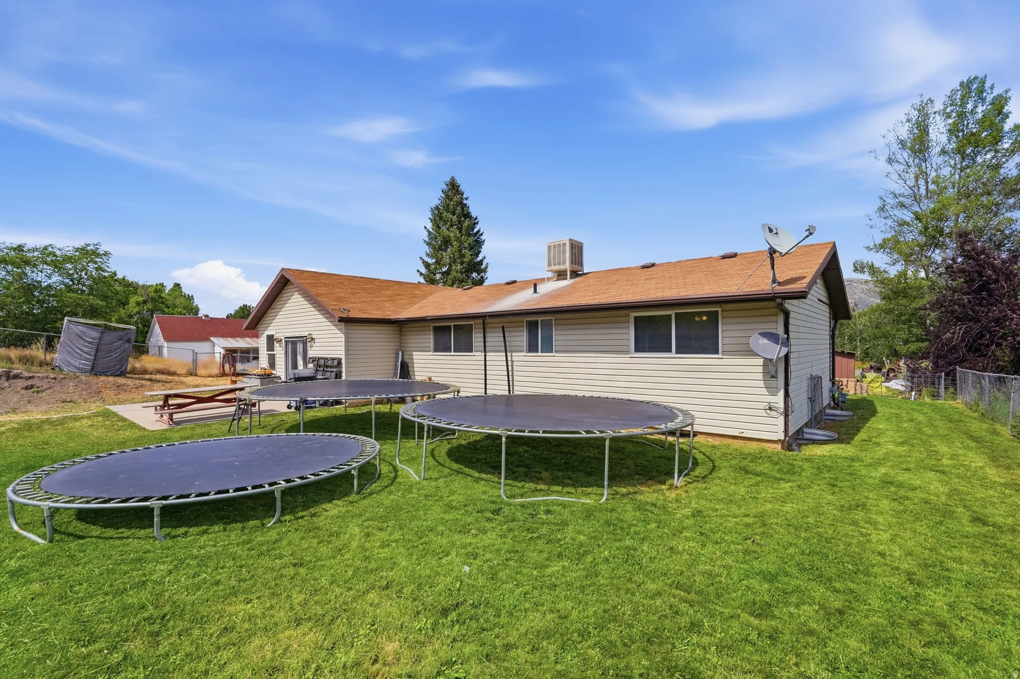 Expansive backyard featuring a manicured lawn, a concrete patio area, and mature trees
