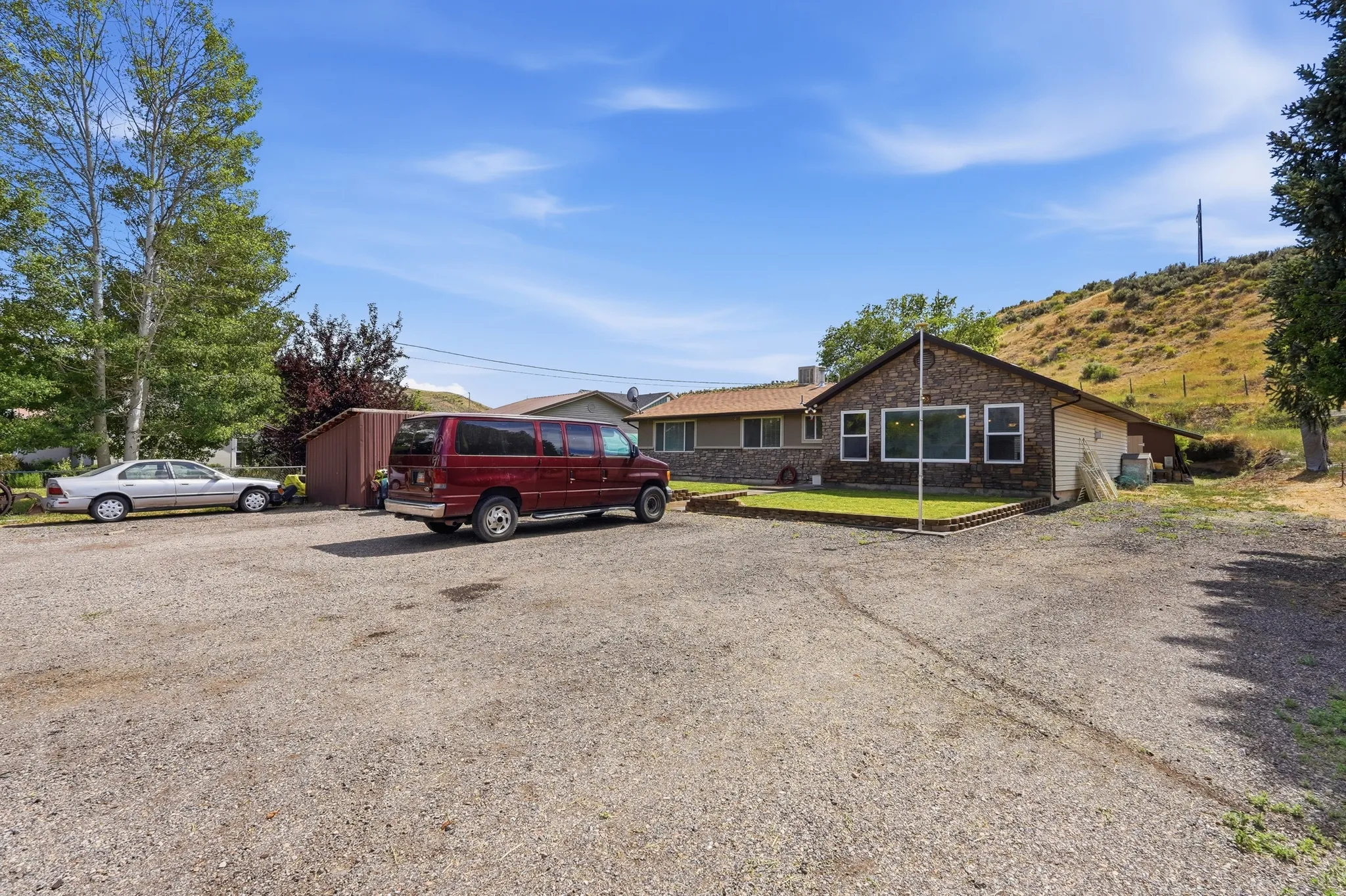 Ranch-style residence featuring a stone facade and a gravel parking area