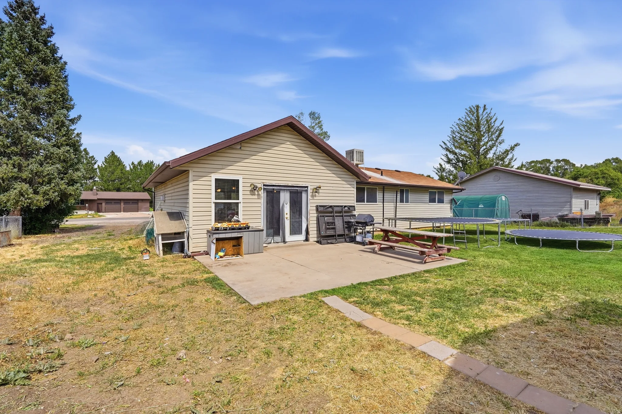 Rear exterior featuring beige horizontal siding, a concrete patio, and a double glass door entry