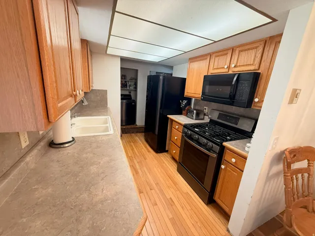 Kitchen featuring wood-finish flooring, light wood cabinetry, and neutral countertops