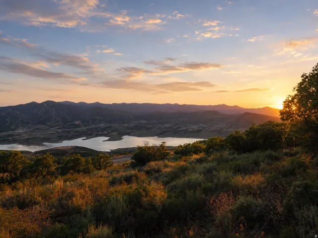 Expansive mountain and lake scenery with a prominent sunset