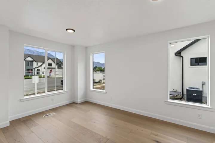 Bright interior space featuring light wood-finish flooring, recessed ceiling lighting, and multiple windows with white trim