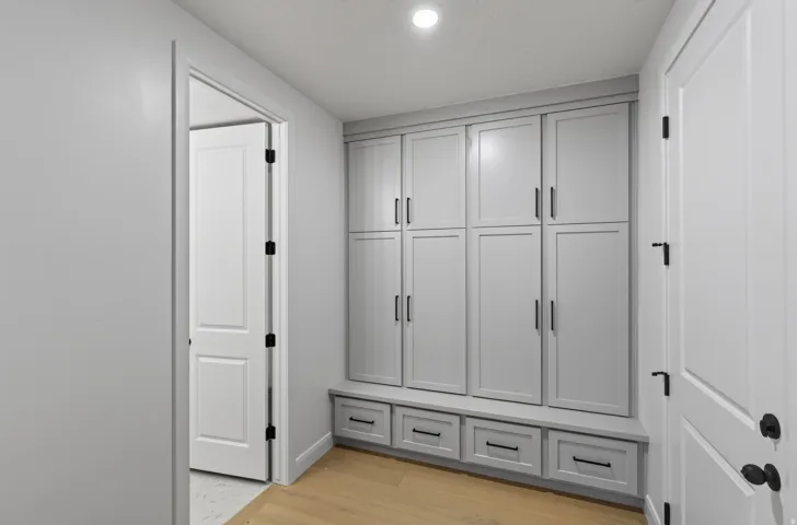 Built-in storage cabinetry with a light gray finish, black hardware, and integrated bench seating