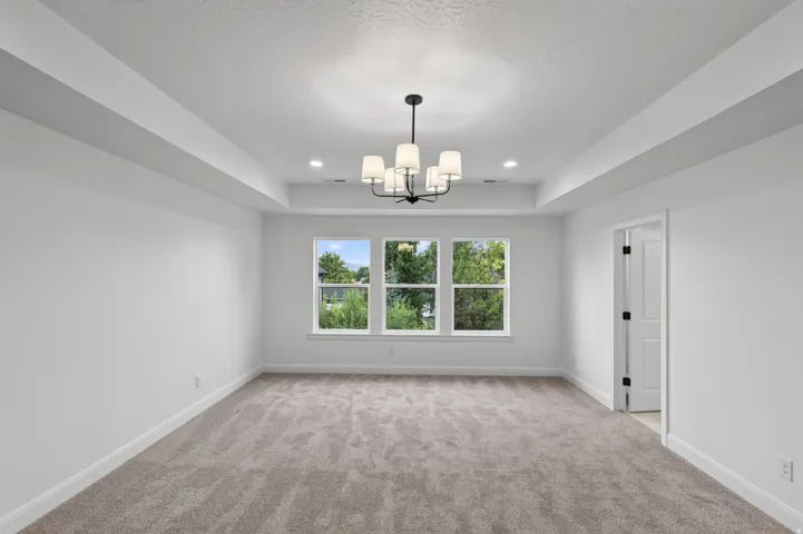 Spacious room with a tray ceiling, recessed lighting, and a contemporary chandelier