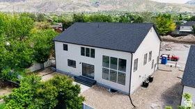 Contemporary architectural design featuring a crisp white exterior, dark pitched roof, and black-framed windows