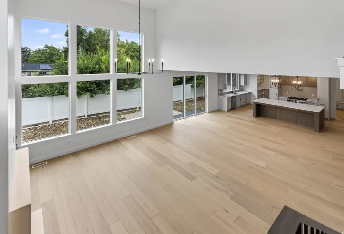 Open-concept living space featuring high ceilings, light wood-finish flooring, and a contemporary chandelier