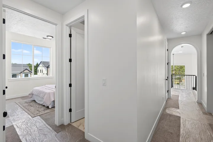 Hallway featuring recessed lighting, an arched entryway, and dark metal railing