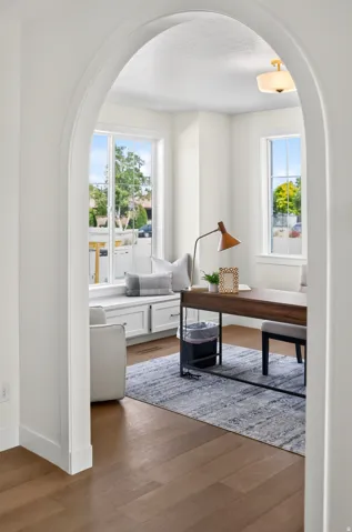 Archway entry leading to a room featuring abundant natural light, a window seat with integrated storage, wood-finish flooring, and a semi-flush mount ceiling fixture