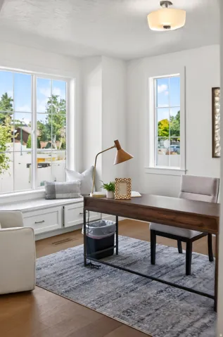 Bright room with wood-finish flooring featuring a built-in window seat with integrated cabinetry