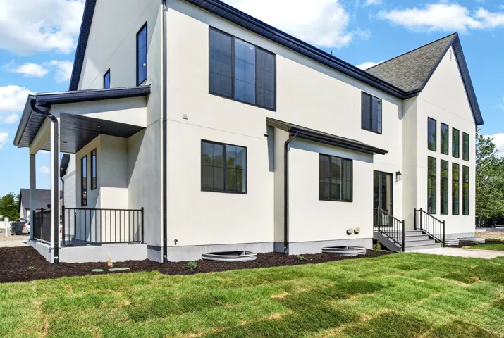 Contemporary stucco exterior with a covered patio featuring black railings