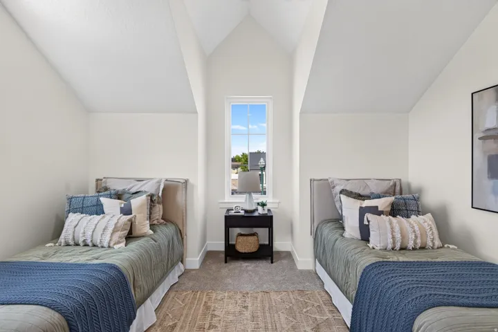 Vaulted ceiling bedroom featuring a central window, carpeted flooring, and white baseboards