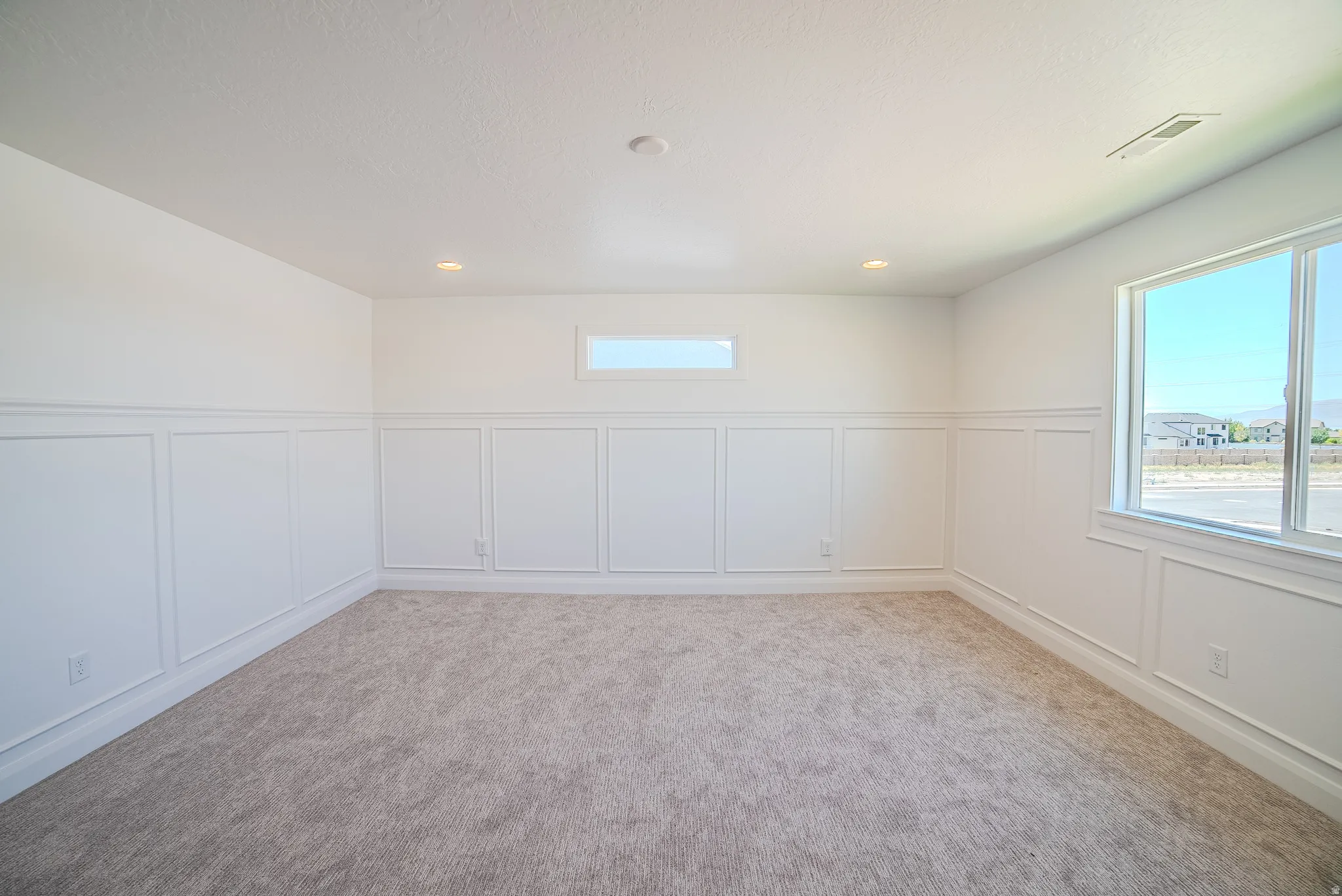 Bright interior space featuring wainscoting, recessed lighting, and soft gray carpeting