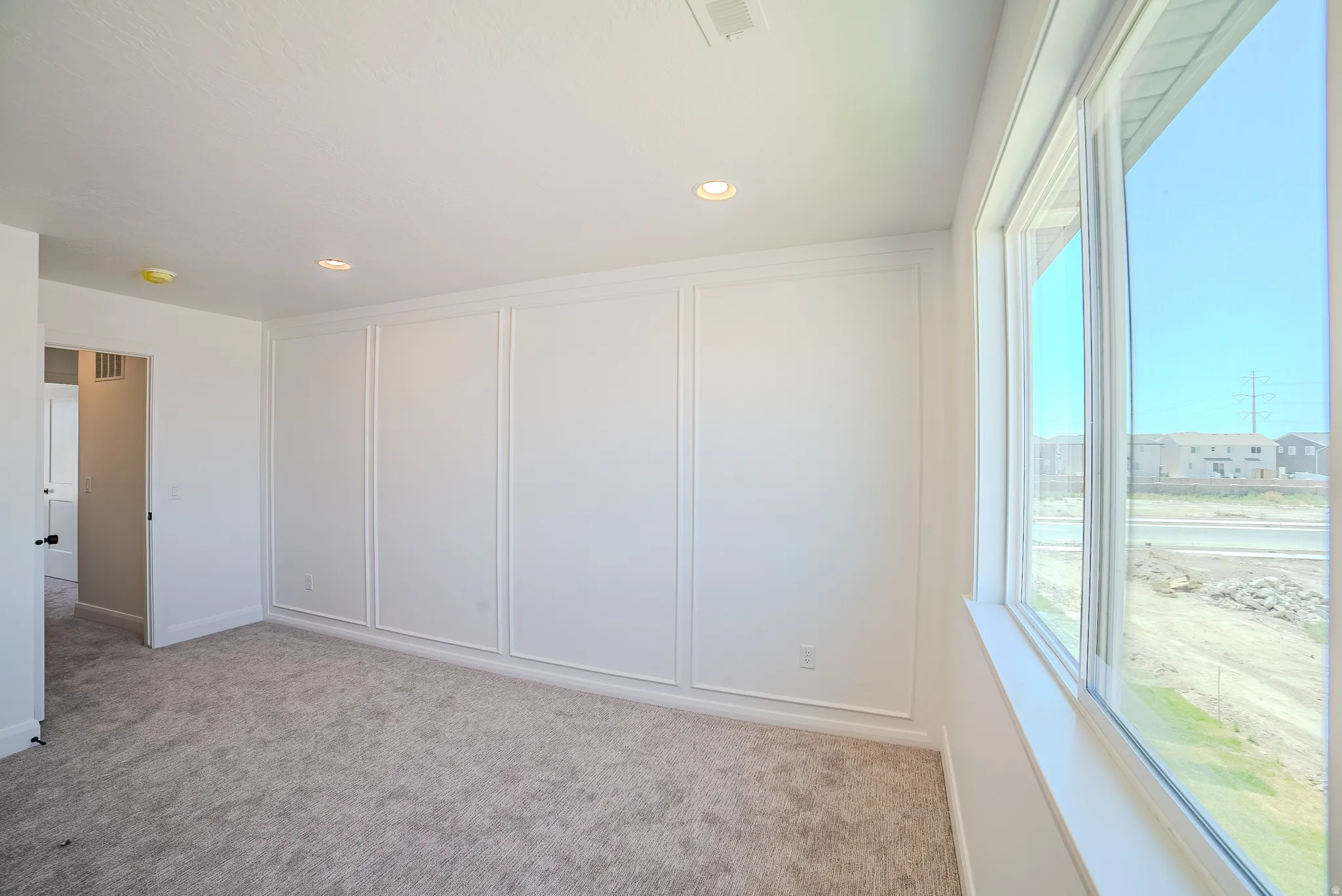 Wall paneling detailing, recessed lighting, and large windows with white trim